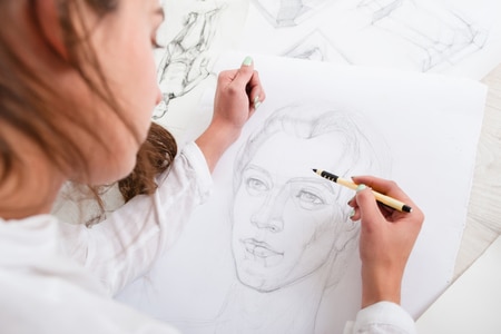woman drawing a portrait of a man with a pencil